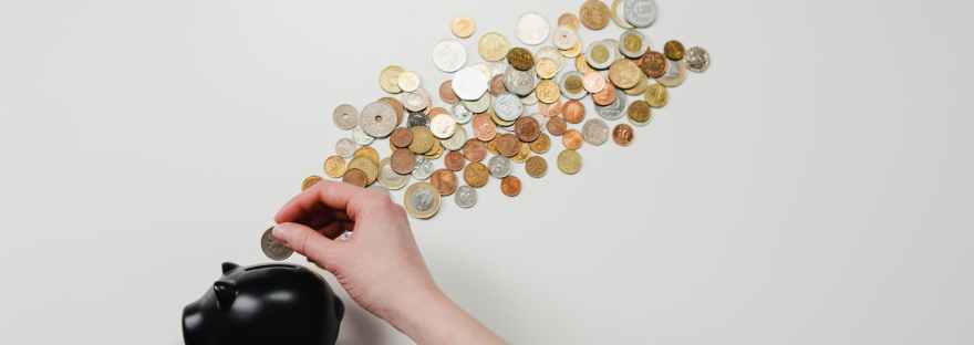 person putting coin in a piggy bank
