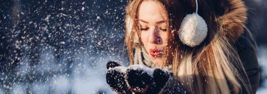 woman blowing snow from hand