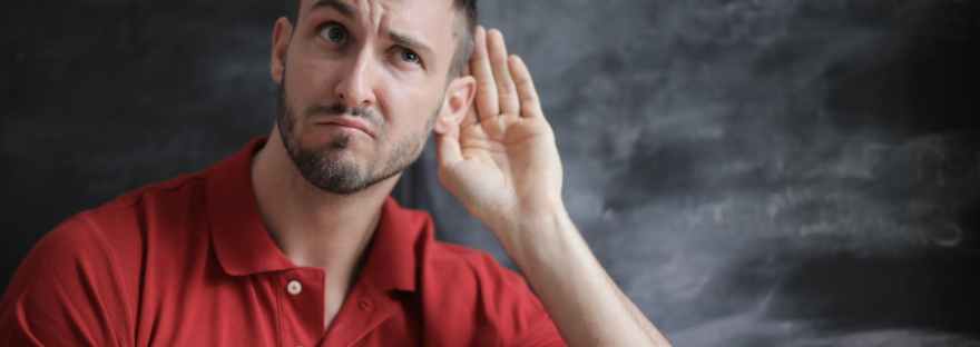 man in red polo shirt sitting near chalkboard
