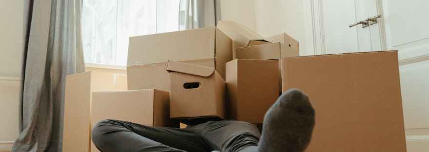 person in black pants sitting on brown cardboard box