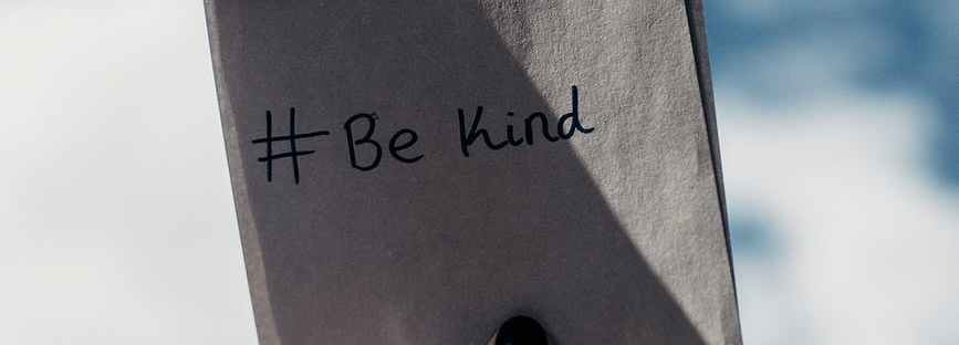 person holding note with be kind text